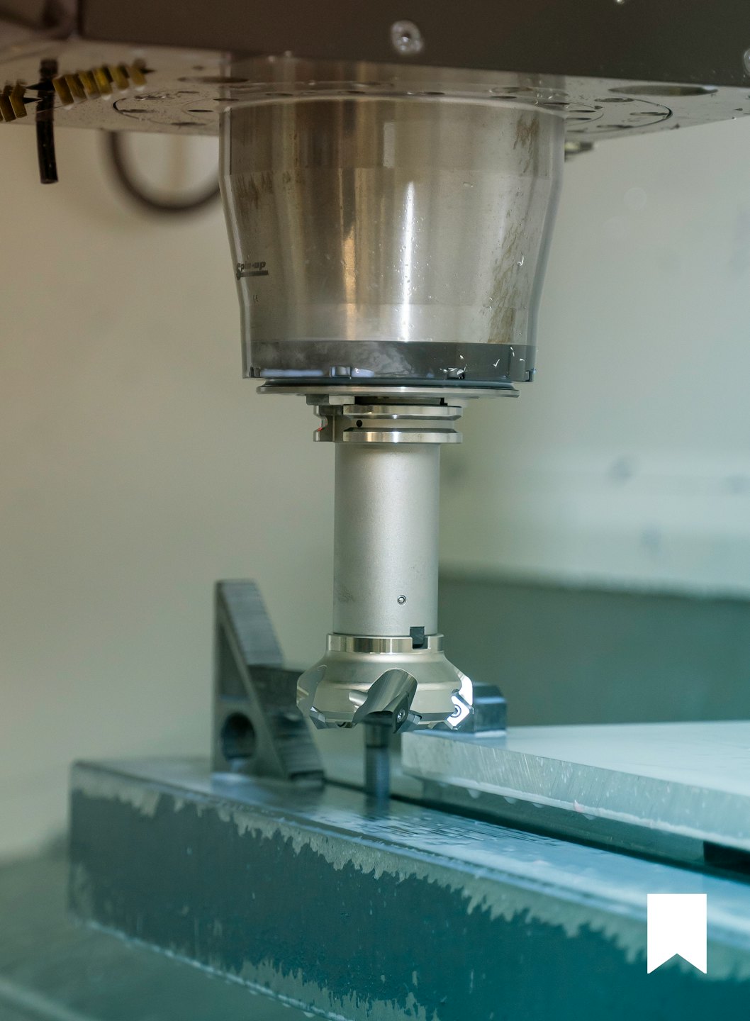Głowica frezująca CNC obrabiająca metalowy element obrabiany z chłodziwem.
