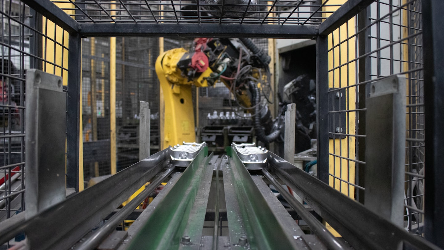 Ramię robota pracuje na linii produkcyjnej z przenośnikami taśmowymi.
