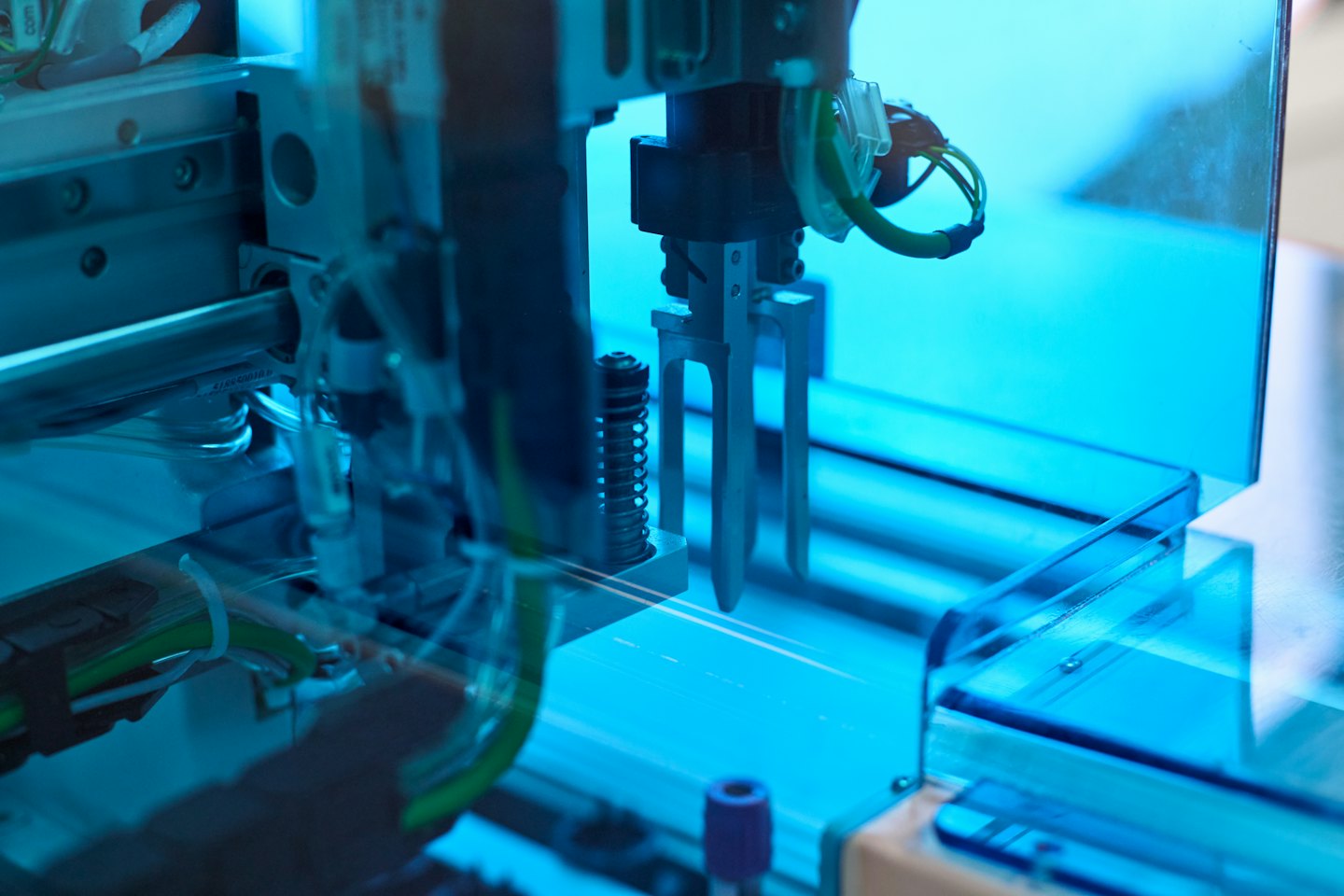 Ramię robota pracujące ze skomplikowaną maszynerią i okablowaniem.
